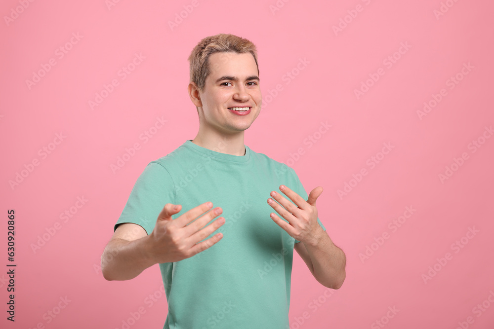 Happy man inviting to come in against pink background Happy man inviting to come in against pink background