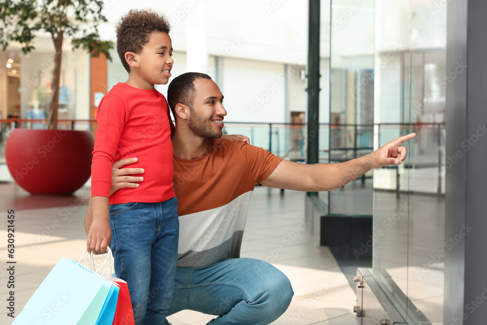 Obraz premium Family shopping. Happy father and son with colorful bags in mall
