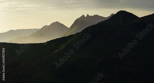 Panorama of abstract norwegian landscape at sunset, Smaltinden, Luröy, Helgeland, Nordnorge. Post summer storm dusk with mountain silhouettes. Green details in dark mountains scandinavia. Sommarnatt