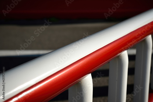 A guardrail with a glossy red and white finish that denotes a no-entry zone is shown in detail in a macro photograph