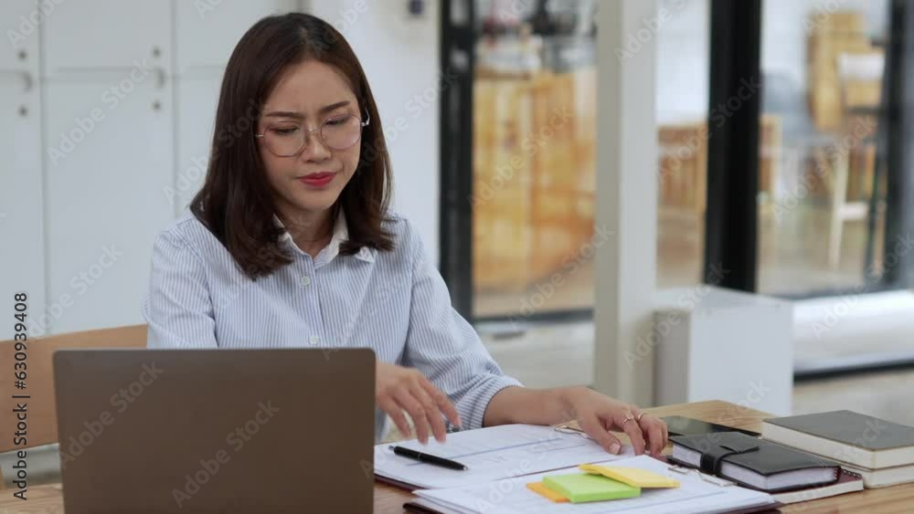 Tired business woman in stress works at a laptop while sitting at a table at home and holds her hand on her temples Tired business woman in stress works at a laptop while sitting at a table at home and holds her hand on her temples