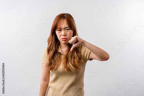 Portrait of displeased offended young Asian woman looks angrily aside doesnt agree with somebodys opinion wears cream clothes isolated over white background
