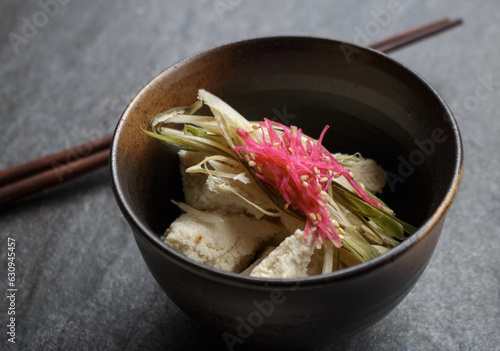 Japanese tofu in brown bowl topped with sliced myoga and ginger