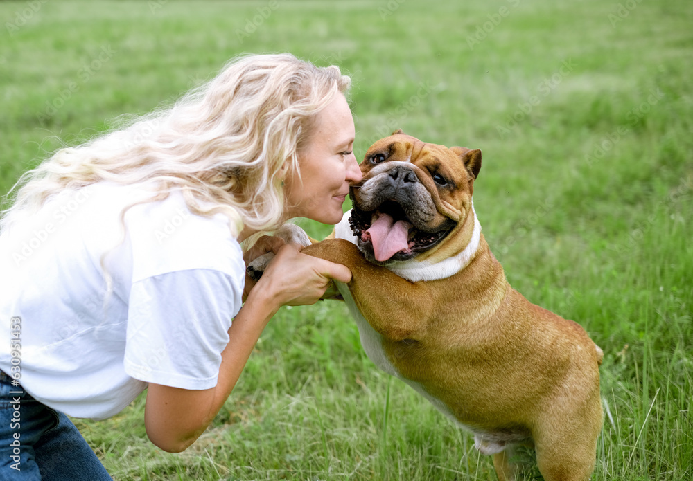 young woman playing with English Bulldog at park young woman playing with English Bulldog at park