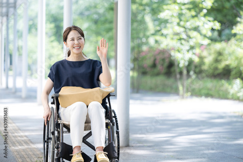 車椅子に乗る若い女性　手を振って挨拶 photo