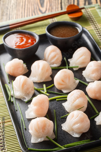 Traditional Asian Prawn or shrimp dumplings hakau, ha kauw or har gow served with sauce on the table. Vertical photo