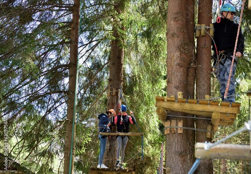 Obraz na płótnie Man and a woman climb the wooden stairs at a height in amusement rope park w salonie