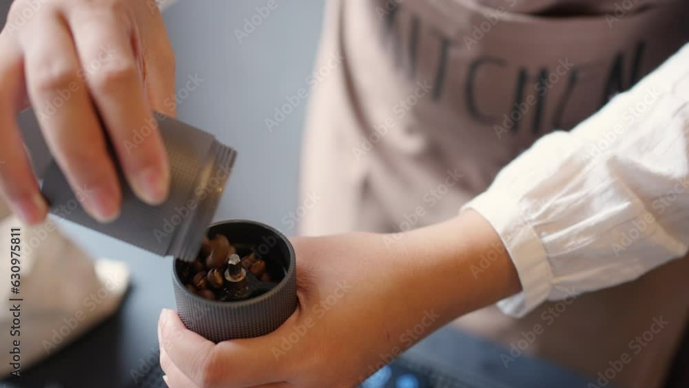 Asian woman barista grinding coffee bean by hand coffee grinder for making aroma scented tasty brewed drip coffee by pouring hot water in kettle through of ground coffee on paper filter into glass pot Asian woman barista grinding coffee bean by hand coffee grinder for making aroma scented tasty brewed drip coffee by pouring hot water in kettle through of ground coffee on paper filter into glass pot