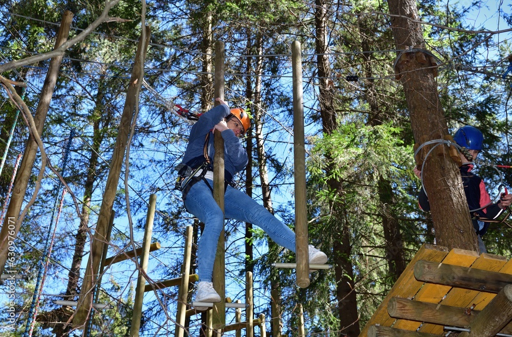 Man and a woman climb the wooden stairs at a height in amusement rope park