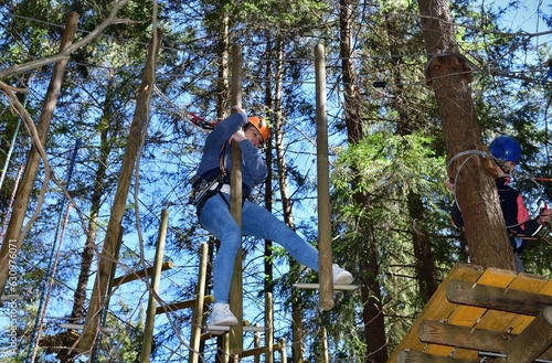 Obraz na płótnie Man and a woman climb the wooden stairs at a height in amusement rope park w salonie