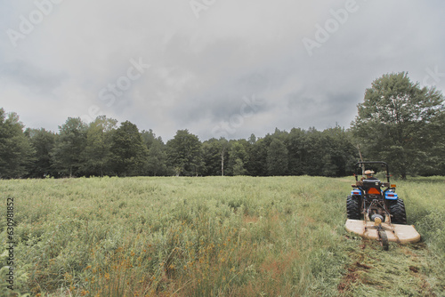 Tractor Mowing on Overcast Day near Forest
