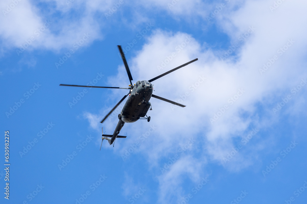 Silhouette of a helicopter flying in the blue sky with clouds Silhouette of a helicopter flying in the blue sky with clouds