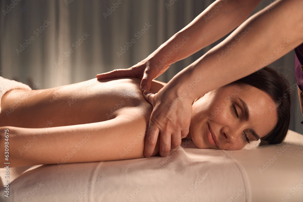 Obraz premium Masseuse massaging trigger point on client shoulder blade