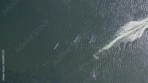Top down aerial view of motorboat racing past currach boats tethered to buoy photo