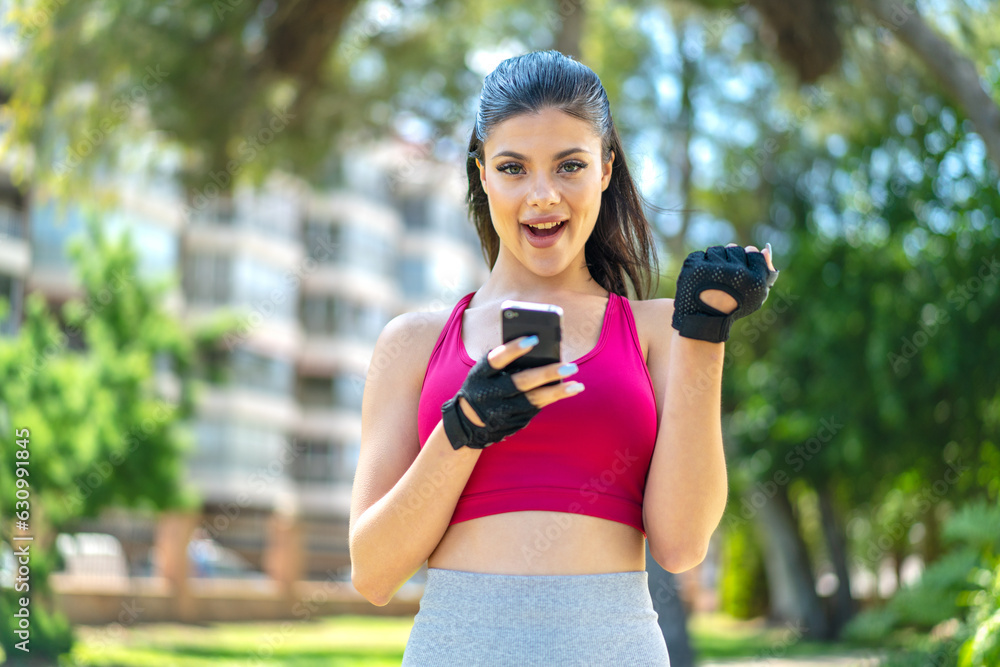 Young pretty sport woman at outdoors surprised and sending a message Young pretty sport woman at outdoors surprised and sending a message