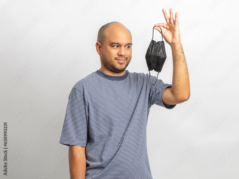 Naklejka premium Handsome young man smiling and happy with protection mask. Charming male standing with on isolated white background. Asian people pose with white backdrop.