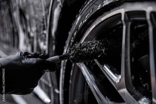 Obraz na płótnie Employee of a car wash or car detailing studio cleans the aluminum rims of a modern car w salonie