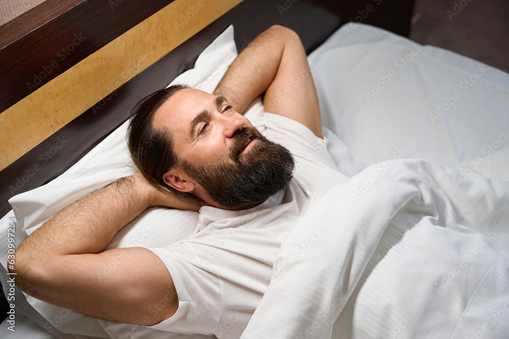 Middle-aged man lies on a snow-white bed Middle-aged man lies on a snow-white bed