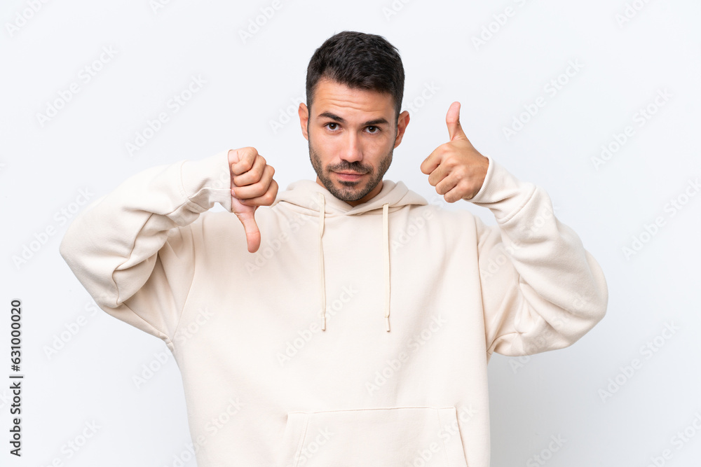 Young caucasian man isolated on white background making good-bad sign. Undecided between yes or not Young caucasian man isolated on white background making good-bad sign. Undecided between yes or not