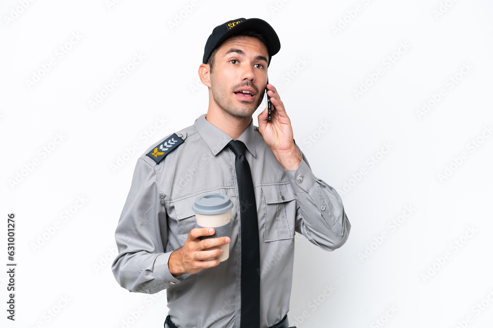 Young safeguard man over isolated white background holding coffee to take away and a mobile Young safeguard man over isolated white background holding coffee to take away and a mobile