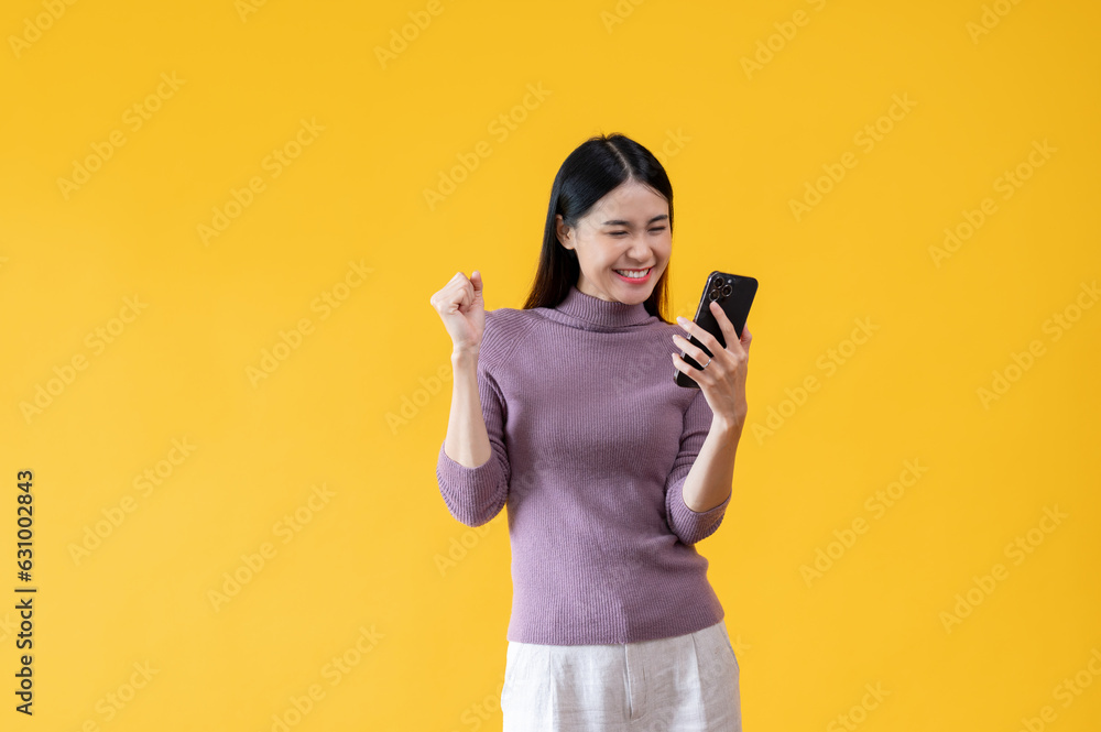A cheerful young Asian woman is looking at her smartphone with a happy face. A cheerful young Asian woman is looking at her smartphone with a happy face.