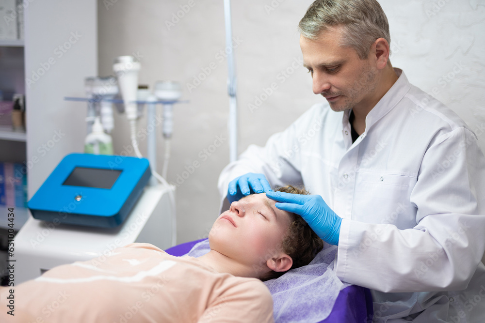 a cosmetologist doctor makes cosmetic procedures on the face of a young guy in a beauty salon a cosmetologist doctor makes cosmetic procedures on the face of a young guy in a beauty salon