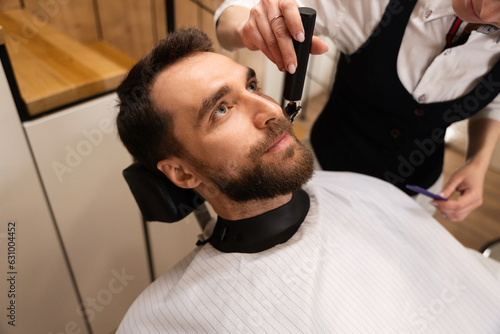 Barber cuts the beard and mustache to the client