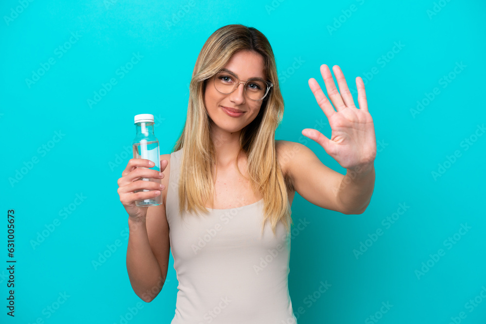 Young Uruguayan woman with a bottle of water isolated on blue background counting five with fingers Young Uruguayan woman with a bottle of water isolated on blue background counting five with fingers