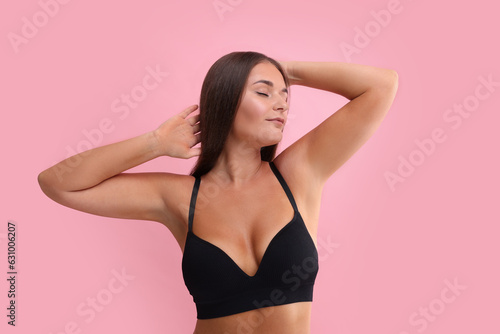 Portrait of young woman with beautiful breast on pink background