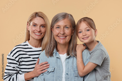 Three generations. Happy grandmother, her daughter and granddaughter on beige background