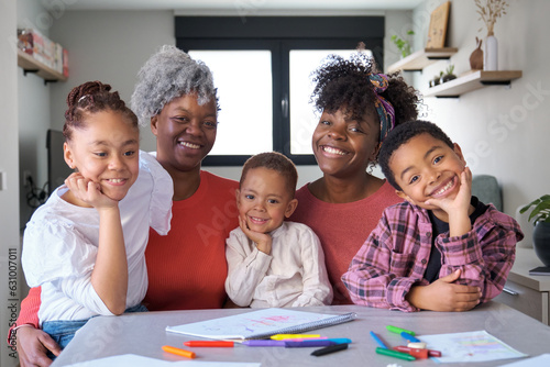 Obraz na plátně Portrait of a happy african horizontal extended family looking at camera and smiling at home