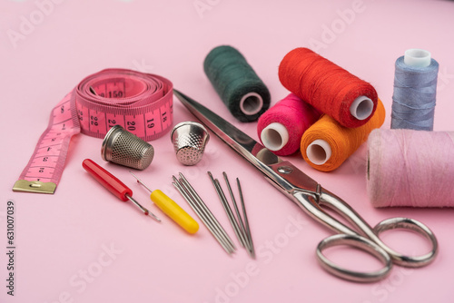 various tailor accessories and tools for tailoring on a pink background