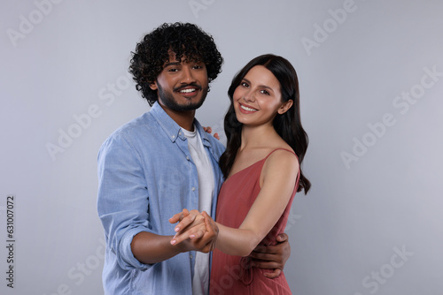 International dating. Happy couple dancing on light grey background
