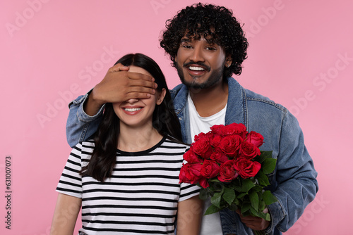 International dating. Handsome man presenting roses to his beloved woman on pink background