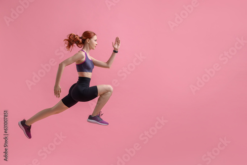Fototapeta Naklejka Na Ścianę i Meble -  Young woman in sportswear jumping on pink background, space for text