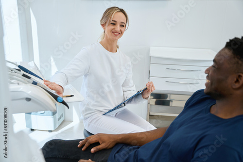 Friendly dental technician showing to male client dental tools