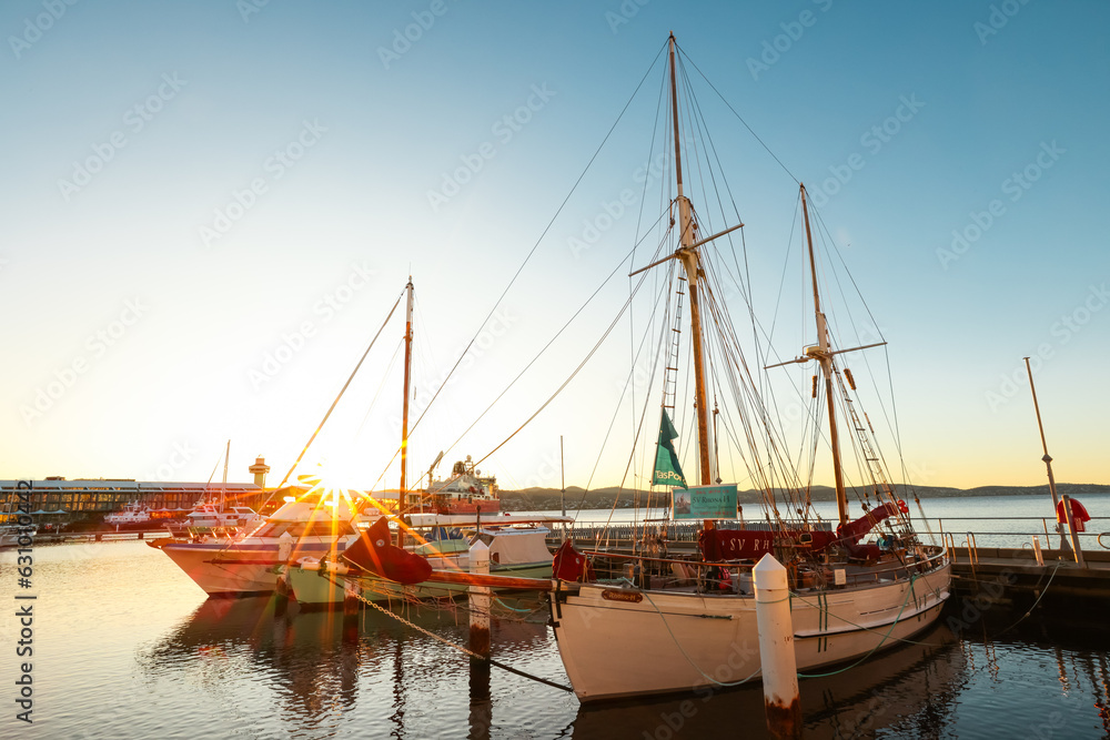 An old sailing ship in a port with a beautiful sunrise on the horizon in Hobart, Tasmania