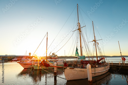 An old sailing ship in a port with a beautiful sunrise on the horizon in Hobart, Tasmania