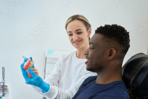 Dental technician showing dental prosthesis to African American client