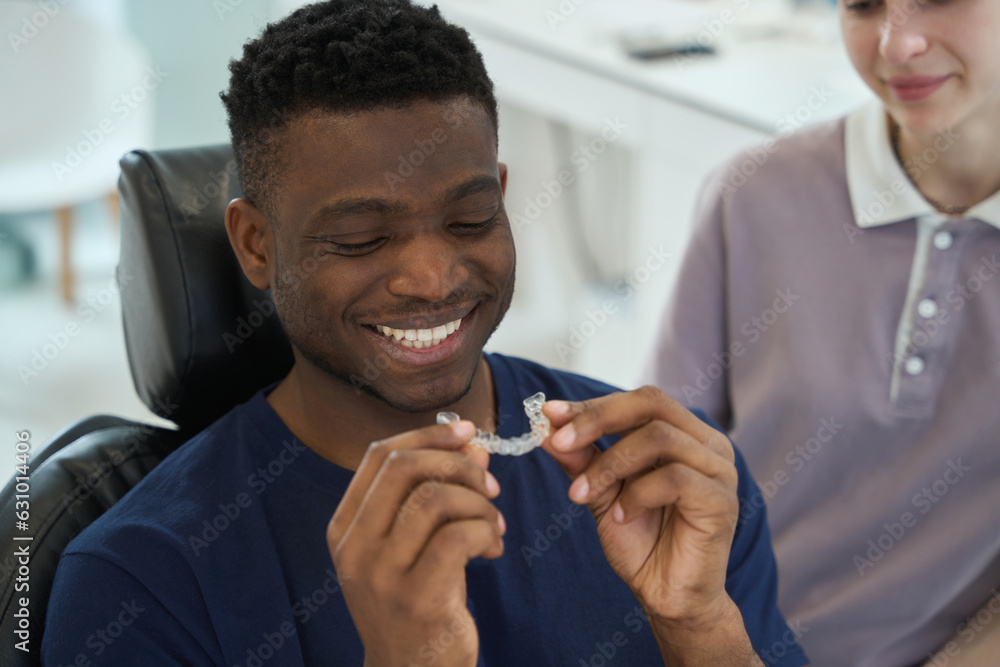 African American man wearing clear braces in order to get rid of malocclusion African American man wearing clear braces in order to get rid of malocclusion