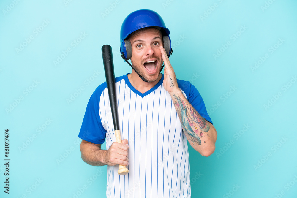 Baseball player with helmet and bat isolated on blue background with surprise and shocked facial expression