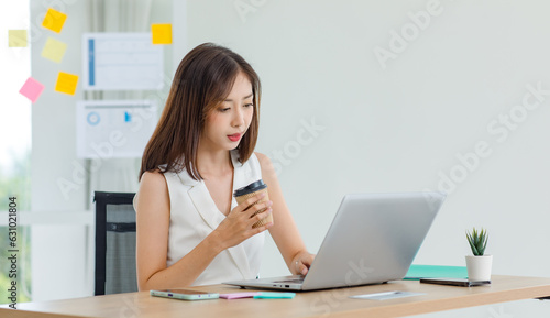 Asian young stressed depressed tired exhausted female businesswoman employee in casual business wear sitting working overtime with laptop notebook computer before deadline at company office workplace