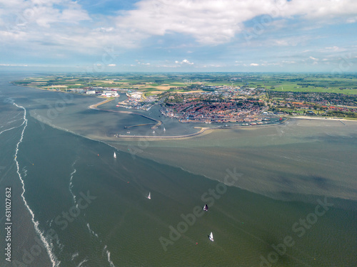 Aerial image of the Frisian sea port of Harlingen, Friesland, the Netherlands. Historic harbour and jetty with old town in background. Small and large ships and yachts on turbulent sea with currents. 