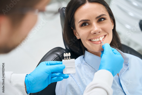 Male doctor stomatologist applying dental crown probe at female client teeth