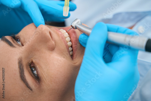 Woman smiling while doctor drilling her unhealthy teeth, close-up