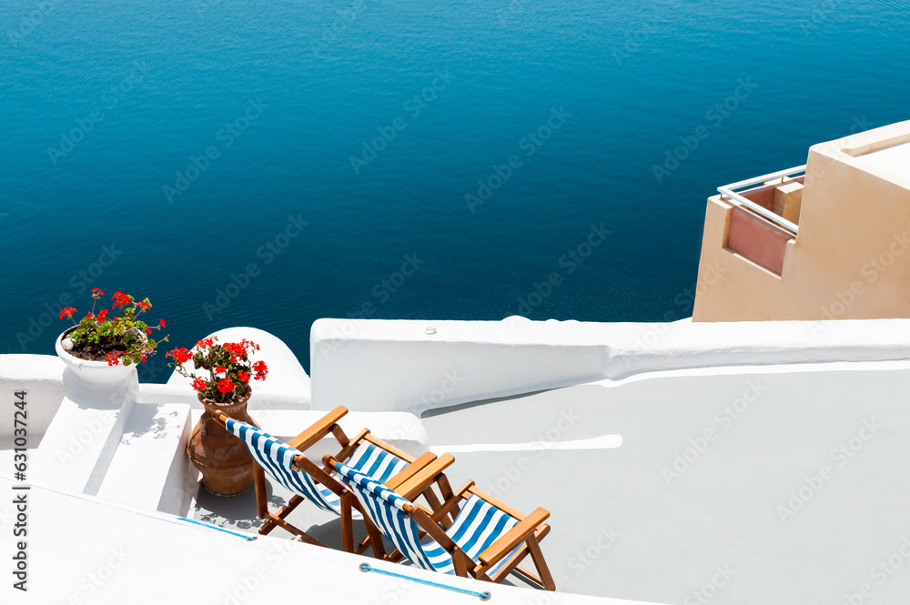 Santorini island, Greece. Chaise lounges on the terrace with sea view.