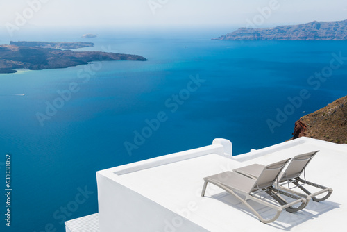 Fototapeta Naklejka Na Ścianę i Meble -  White architecture in Santorini island, Greece. Chaise lounges on the terrace with sea view.