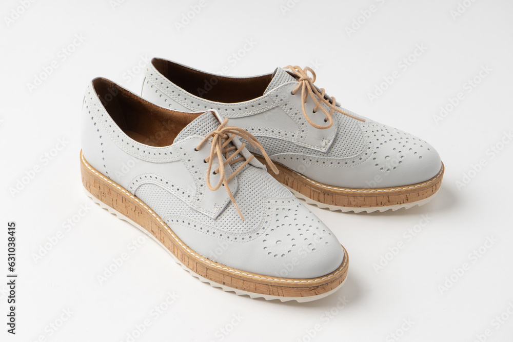 Casual white mid-season leather shoes with white laces and cork soles. New women's shoes on a white background.