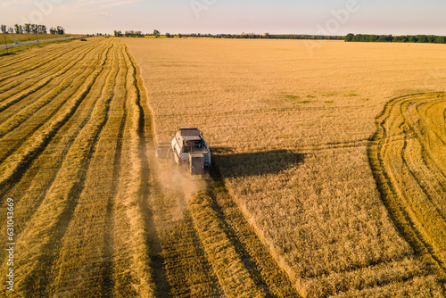 Combine harvester working in field crop of wheat on field. Aerial view