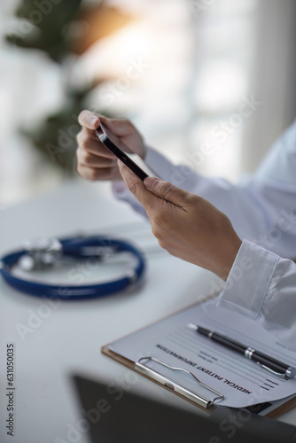 Hands of doctor in white coat using mobile phone, giving virtual online consultation, sending test results, chatting to patients, making video calls and appointments. Remote medical consulting